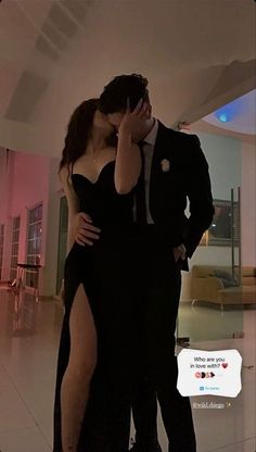 a man in a suit kissing a woman with her hand on her face while she is wearing a thigh high slit dress