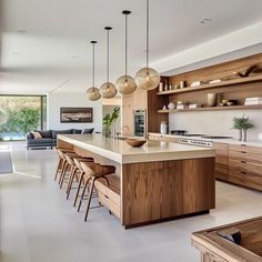 an open kitchen with wooden cabinets and counter tops, along with bar stools in front of the island