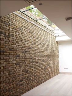 an empty room with a brick wall and skylight