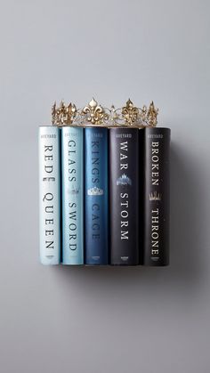 a row of books sitting on top of each other in front of a gray wall