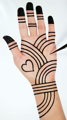 a woman's hand with black and white designs on it, holding a pencil