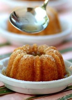 a small cake in a white bowl with a spoon sticking out of it and sitting on a table