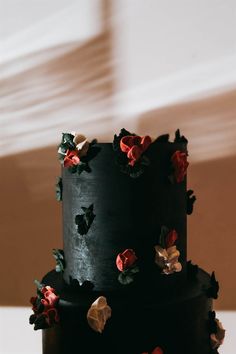 a black cake with red and white flowers on it