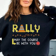 a woman wearing a black sweatshirt that says rally may the course be with you