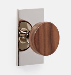 a door handle with a wooden knob on the outside of it and a white wall in the background