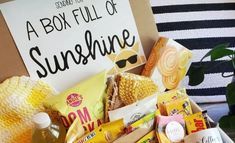 a box full of sunshine snacks and drinks with a sign in the background that reads, some to a box full of sunshine