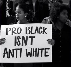 people holding signs that read pro black isn't anti white