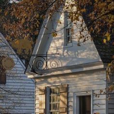 a white house with a black cat sitting on the window sill in front of it