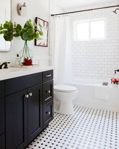 a bathroom with black and white tile flooring and walls, along with a large mirror on the wall