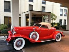 an old red car parked in front of a hotel