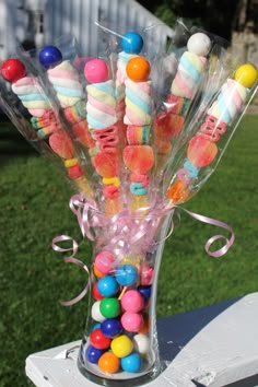 a vase filled with candy and candies on top of a wooden table in the grass