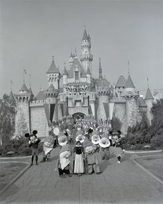 black and white photograph of people in front of mickey mouse's castle