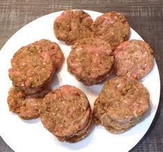 a white plate topped with meat patties on top of a wooden table