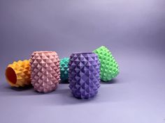 three different colored vases sitting next to each other on a gray surface with grey background