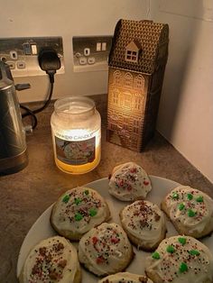 some cookies are sitting on a plate next to a jar of honey and a candle