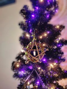 a purple christmas tree with lights and a star ornament hanging from the top