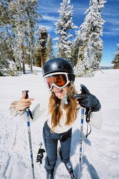 a woman is standing in the snow with her skis on and holding two poles