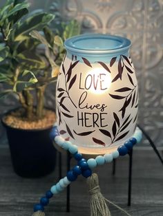 a candle holder with a light that says love lives here on it and beads around the base