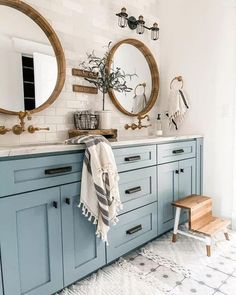 a bathroom with two round mirrors and blue cabinets