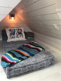 a bed sitting in the middle of a room under a lofted roof with two pillows on top of it