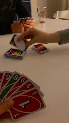 two people playing cards at a table with one person holding the card in their hand