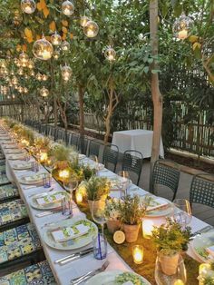 a long table is set up with plates and place settings for an outdoor dinner party