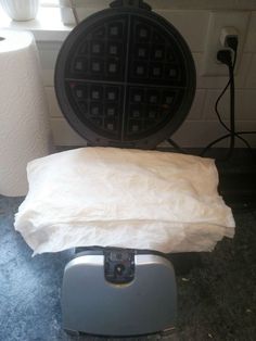 a waffle iron sitting on top of a table next to a toilet paper roll