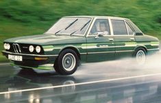 a green car driving down a wet road