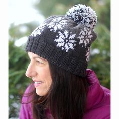 a woman wearing a black and white hat with pom - poms on it