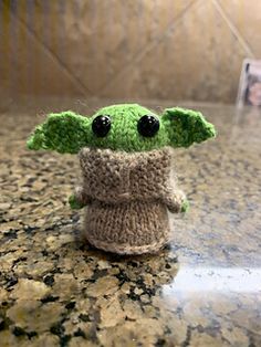 a knitted yoda doll sitting on top of a counter