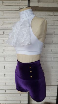 a mannequin with a white top and purple shorts on display in front of a brick wall