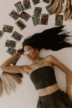 a woman laying on the ground with her hair blowing in the wind and photos scattered around her