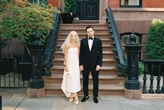 a bride and groom standing in front of the stairs