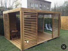 a small wooden structure in the middle of a yard with chairs and tables around it