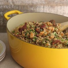 a yellow pot filled with rice and vegetables on top of a table next to plates