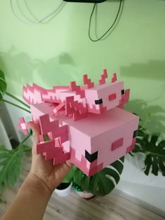 a hand holding up a pink box that looks like an animal with pixeles on it