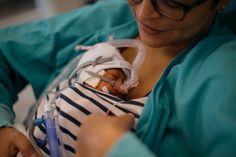 a woman is holding a baby in a hospital bed with an oxygen tube attached to it