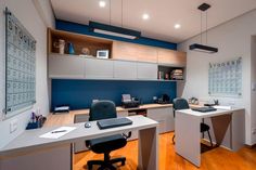 an office with two desks and chairs in front of a wall mounted calendar on the wall