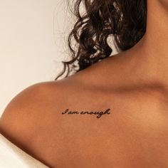 the back of a woman's shoulder with an i am enough tattoo on it