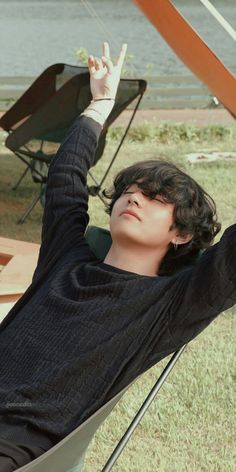 a young man sitting in a chair with his hand up to the sky above him