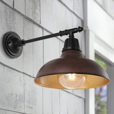 an industrial style light fixture on the side of a building with white brick walls and windows