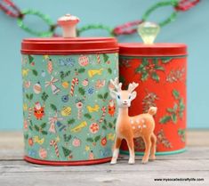 two tin canisters with deer figurines on them sitting next to each other