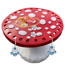 a red stool with white polka dots and blue dangling earrings on it's side