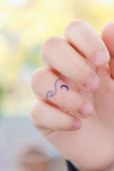 a person holding their hand up with a small tattoo on it's thumb and finger