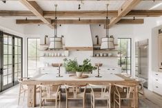 a kitchen with white walls and wooden beams on the ceiling is filled with potted plants