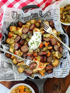 a plate full of sausage, potatoes and carrots with sour cream on the side