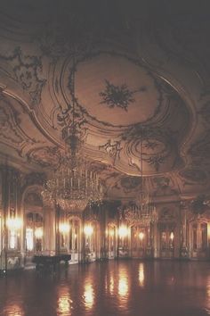 an ornately decorated ballroom with chandeliers and mirrors on the ceiling is lit by candles