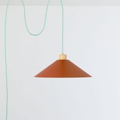 an orange lamp hanging from a green cord on a white wall in a living room