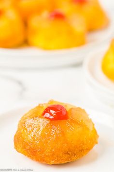 a pineapple upside down pastry on a plate next to some other plates with oranges in the background