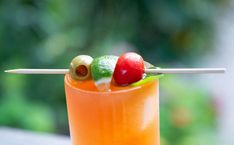 an orange cocktail with fruit on the top and skewers sticking out of it